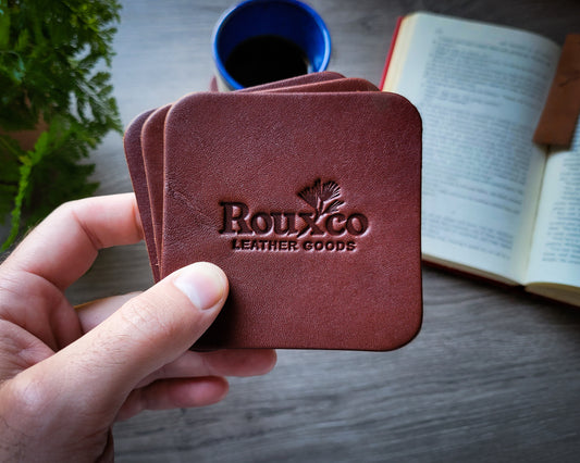 Brown Wickett & Craig leather coaster held in hand with open book in the background